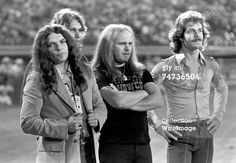 three men standing next to each other in front of a stadium with their arms crossed