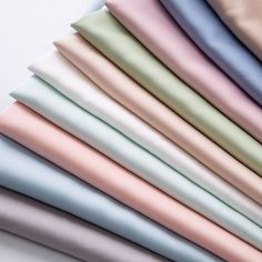 many different colors of satin fabric on top of each other with one folded in the middle