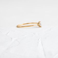 a yellow gold ring with a single diamond on the top, sitting on a white surface