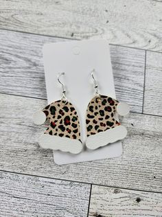 a pair of leopard print earrings on top of a white cardigane paper box