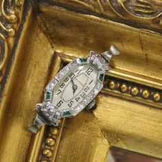 This is a beautifully crafted vintage 18K White Gold Jeweled Swiss made Art Deco watch. Elaborate detailing around the face. Emerald cabochon crown. The top and bottom synthetic emeralds on the left side are chipped, but this does not detract from the watch's overall beauty or functionality. This item is in good condition with only some wear, it has recently been professionally inspected and seems to be running normally. Please review the images provided. Please note, this does not include a ban Emerald Watch, Emerald Art Deco, Emerald Art, Emerald Cabochon, Art Deco Watch, Watch Women's, Vintage Watches Women, Jewelry Lockets, Watches Luxury