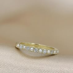 a wedding band with five diamonds on top and bottom, sitting on a fabric surface