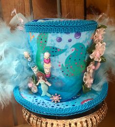 This is a great hat for a tea party or beach theme get together .  This Tea Party Hat is a medium  size.  Measures approx. 6"  and 4.5" tall plus decorations  Has blue & turquoise feathers. It has 2 hat pins. Mermaid tail pick and mermaid  pick on hat.  Hat has white elastic to hold on your head. Elastic goes over your head behind ears &  under your hair. Also included is 2 clips to help stay on if needed. Whimsical Mini Hats With Curved Brim For Beach, Handmade Themed Costume Hats And Headpieces For Themed Events, Handmade Costume Hats And Headpieces For Themed Events, Handmade Wide Brim Top Hat For Party, Whimsical Bucket Hat For Beach, Whimsical Handmade Mini Hat For Beach, Handmade Party Top Hat With Curved Brim, Handmade Whimsical Mini Hats For Beach, Handmade Top Hat With Curved Brim For Party