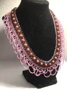 a necklace with pink beads on a black mannequin