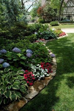 a garden filled with lots of flowers next to a lush green field and large building