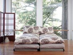 a large bed sitting on top of a hard wood floor next to a tall window