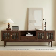 a living room with an entertainment center, lamp and pictures on the wall above it