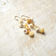 three pairs of dangling earrings with pearls on them sitting on top of a wooden table