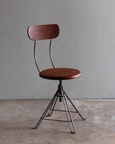 a wooden chair sitting on top of a metal frame floor next to a gray wall