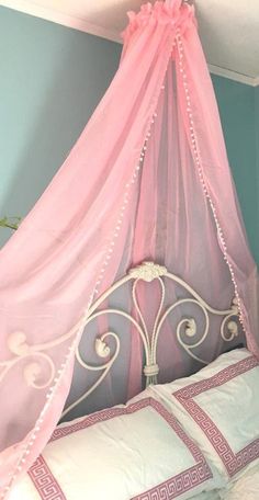 a pink canopy bed in a bedroom with blue walls