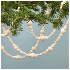 a pine tree branch with white ornaments hanging from it's branches on a clear day