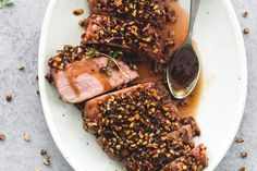 some meat is sitting on a plate with sauce and seasoning next to the meat