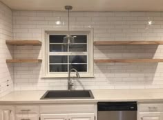 an empty kitchen with white cabinets and open shelving