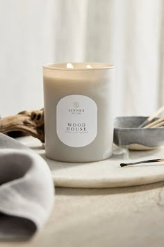 a white candle sitting on top of a table next to spoons and utensils