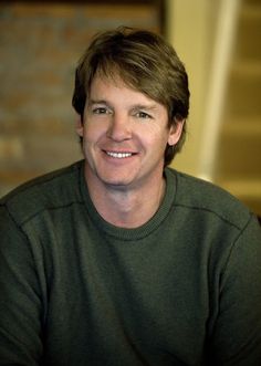 a smiling man in a green shirt is looking at the camera