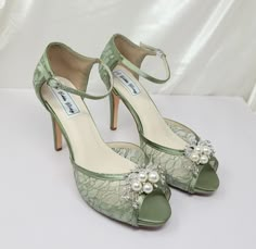 a pair of green high heel shoes with pearls on the toes and bows at the ankle