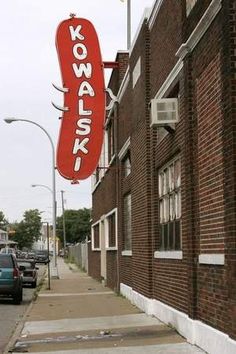 a kodak sign hanging from the side of a building next to a street with parked cars