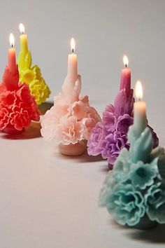 four candles with flowers on them sitting next to each other