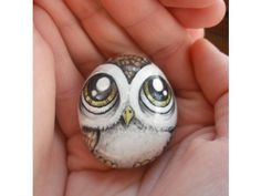 a hand holding a small owl figurine in it's palm