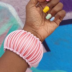 a woman's hand holding a pink and yellow manicure on her left wrist