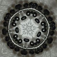 a black and white beaded brooch sits in the middle of a circular pattern