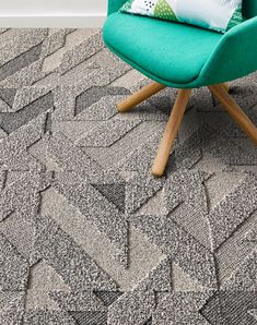 a green chair sitting on top of a carpet covered in lots of grey and white shapes