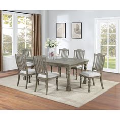 a dining room table with six chairs and a rug in front of the window,