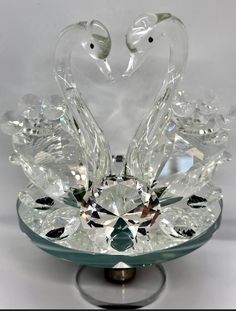 a glass swan sculpture on top of a crystal bowl with two birds in the middle