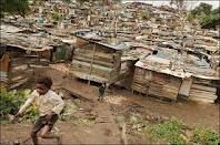 a young boy is running down a dirt path in front of shacks and houses