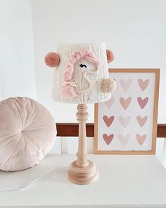 a lamp that is sitting on top of a table next to a stuffed animal and some pictures