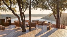 an outdoor deck with chairs and tables next to trees