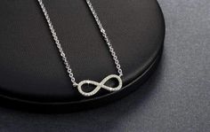 Centered between the two lengths of shiny silver tone chain, this miniature eternity symbol appears to float along the neck. Completely encrusted in micro CZ stones creating incredible shimmer. At only 2 cm this is truly subtle and graceful. This necklace is perfect for women, teens or young children. Length: 18 inch chain Stones: CZ Metal: Sterling Silver, 3 layers of platinum plating. Comes in a gift box. (Reg $45.99) Silver Infinity Clavicle Chain Jewelry, Silver Infinity Dainty Necklace, Silver Infinity Necklace In Dainty Style, Silver Dainty Infinity Necklace, Dainty Silver Infinity Necklace, Silver Infinity Clavicle Chain Necklace, Silver Infinity Chain Jewelry, Infinity Necklace With Diamond Accents In Cubic Zirconia, Cubic Zirconia Infinity Necklace With Diamond Accents