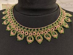 a green and gold necklace on top of a black mannequins neckline