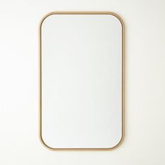 a square mirror on the wall with a wooden frame around it and a white background