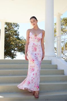 a woman in a pink dress standing on some steps