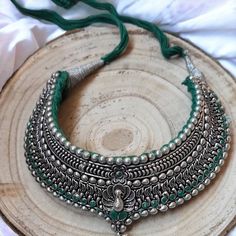 An amazing, metal necklace with silver-colored earrings. The main theme of this jewelry is an Indian peacock, which can be found on the necklace. Additionally, it is decorated with green ribbon   Necklace - maximum length 45 cm, easily adjustable with a string.  Earrings - Jhmka length 4.5 cm, diameter 3.5 cm.