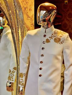 two mannequins dressed in white clothing with gold designs on their faces and arms