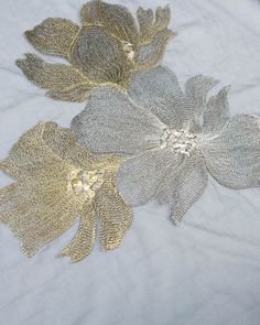 two silver and gold flowers on a white cloth