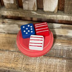 two red, white and blue magnets sitting on top of a wooden table next to each other