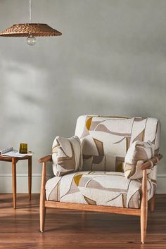 a living room with a chair, table and lamp hanging from the ceiling over it