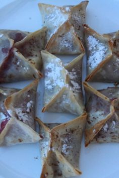 several pastries are arranged on a plate with powdered sugar and jelly toppings