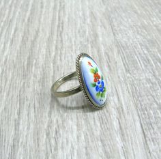 "Finift enameled jewelry, USSR vintage ring with enamel painting, retro statement ring for woman, her anniversary gift, Red poppy and blue cornflower ring. This Russian hand painted enamel ring features red Poppy flower along with blue cornflower, surrounded with green leaves on baby blue background Size: 6 1/2 ( US and Canada ), N, O 1/2, Q( UK and Australia ), 17, 17 1/4, 18 ( European ). The enamel painted oval cabochon is 10 mm wide and 22 mm long. It is set in silver tone metal cast with a Antique Enamel Ring As A Gift, Vintage Flower Shaped Rings For Gift, Handmade Retro Rings As Gift, Oval Enamel Rings For Gifts, Hand Painted Oval Enamel Jewelry, Antique Round Enamel Ring For Gift, Antique Round Enamel Ring Gift, Vintage Oval Enamel Ring Gift, Vintage Blue Enamel Rings