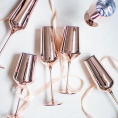 several wine glasses are lined up next to each other on a white surface with ribbons