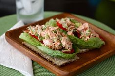 a wooden plate topped with lettuce and chicken salad