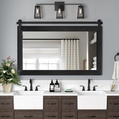 a bathroom vanity with two sinks and a large mirror above it, in front of a window