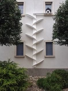 a tall white building with blue shutters on the windows and trees in front of it