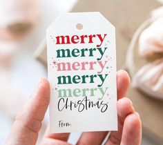 a person holding up a christmas gift tag with merry lettering on the front and bottom