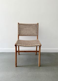 a wooden chair with woven seat and back rests against a white wall in an empty room