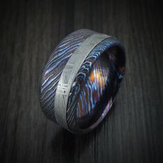 a ring that is sitting on top of a wooden table with blue and orange designs