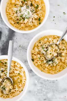 three bowls of macaroni and cheese soup with two spoons on the side